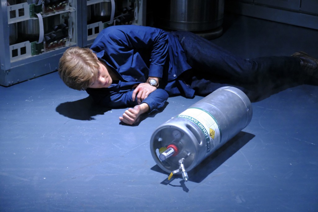 Mac (Lucas Till) est allongé sur le sol à côté d'une bonbonne d'oxygène.