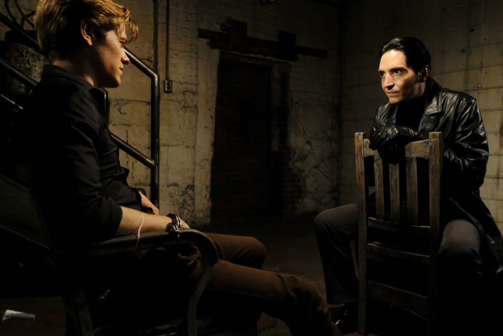 Murdoc (David Dastmalchian) est assis sur une chaise face à MacGyver (Lucas Till) qui est son prisonnier.