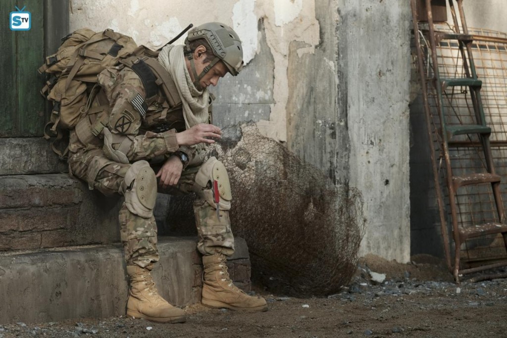 Au cours d'une mission en Afghanistan, Mac (Lucas Till) est assis sur des marches d'escaliers et utilise son couteau suisse.