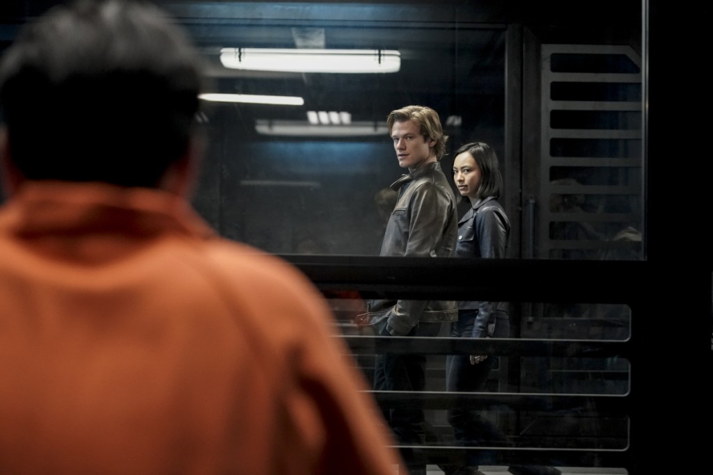 Mac (Lucas Till) et Desi (Levy Tran) arrivent devant la cellule de Murdoc en le fixant droit dans les yeux.