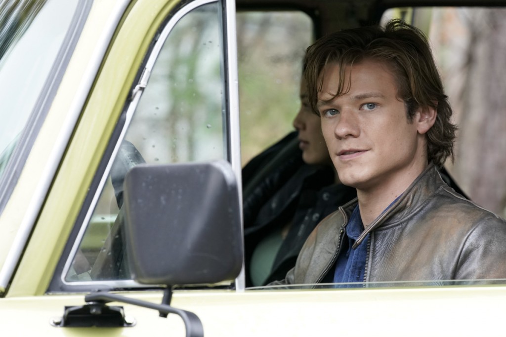 MacGyver (Lucas Till) est au volant d'une voiture.