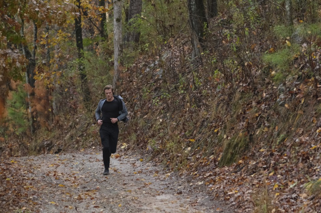 MacGyver (Lucas Till) fait son footing en pleine forêt.