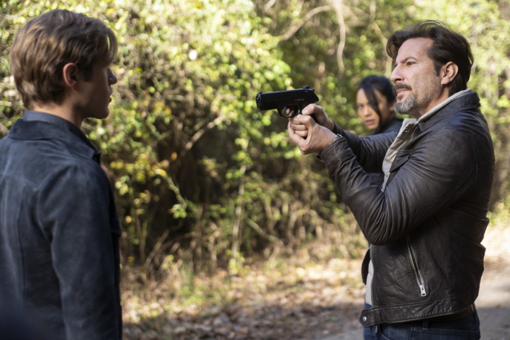 Russ (Henry Ian Cusick) pointe son arme sur MacGyver (Lucas Till).