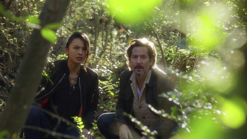 Desi (Levy Tran) et Russ (Henry Ian Cusick) se cachent dans la forêt en attendant le signal de Mac et Riley.