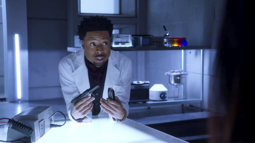 Bozer (Justin Hires) se trouve dans le laboratoire de Phoenix et tient une arme entre ses mains.