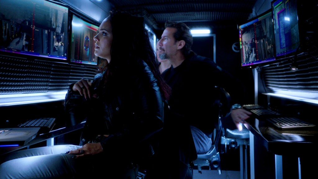 Riley (Tristin Mays) et Russ (Henry Ian Cusick) observent les caméras de surveillances afin de guider Desi durant le hold-up.