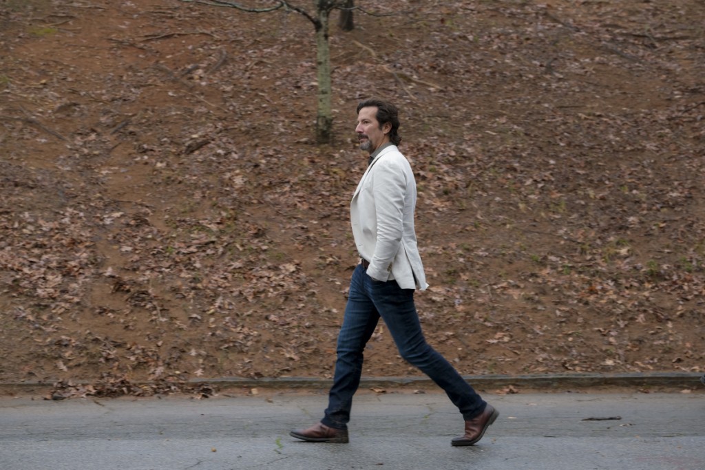 Russ (Henry Ian Cusick) marche tranquillement dans un parc.