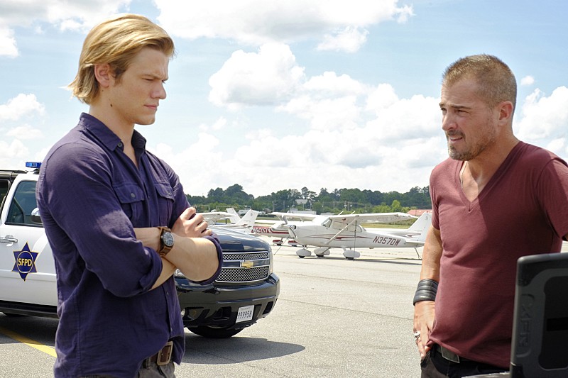 Mac (Lucas Till) et Jack (George Eads) discutent ensemble sur le tarmac d'un aéroport.