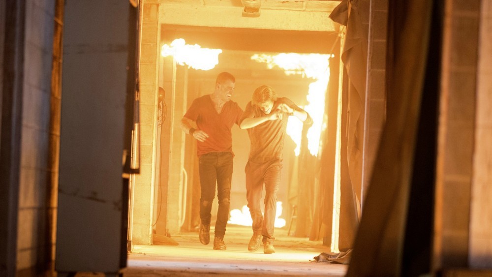 Jack (George Eads) et MacGyver (Lucas Till) tentent de sortir d'un bâtiment en feu.