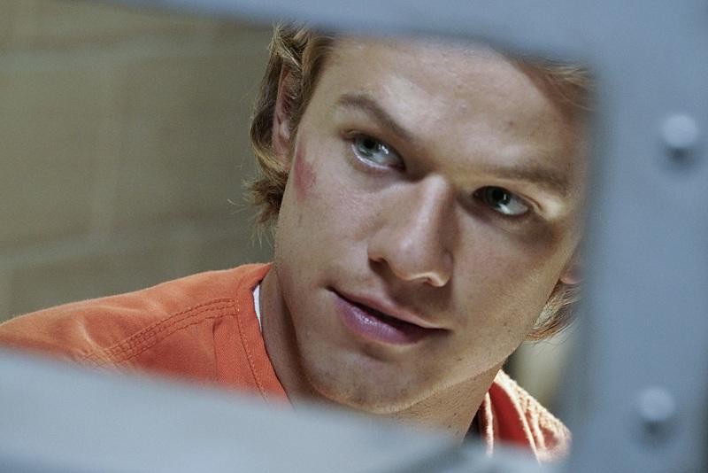MacGyver (Lucas Till) se trouve en prison et porte la tenue orange.