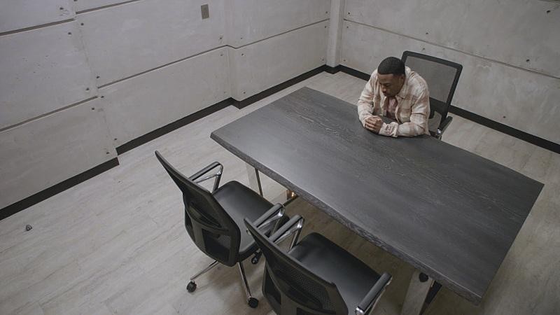 Bozer (Justin Hires) se trouve seul dans une salle d’interrogatoire.